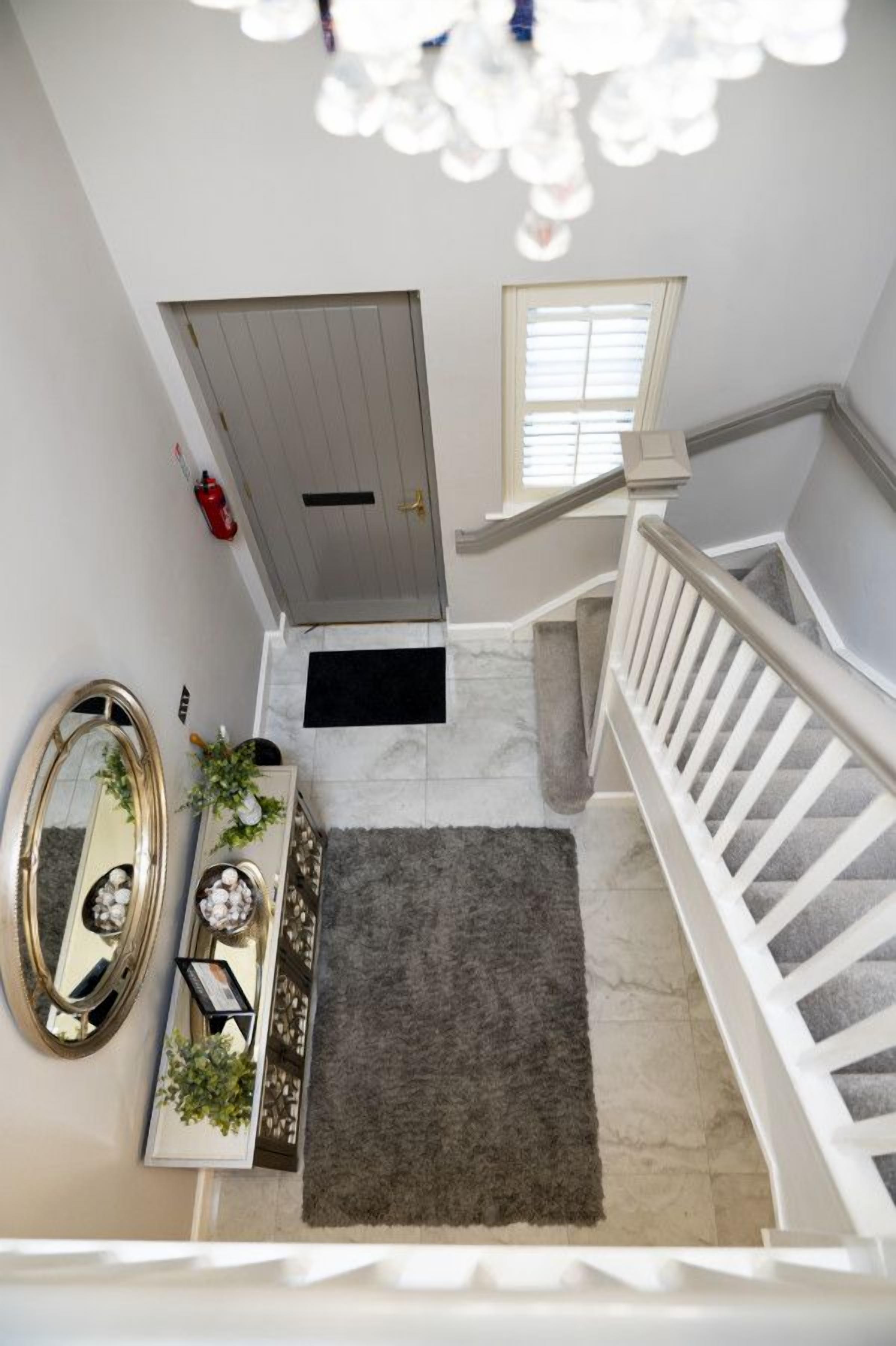 A staircase with a white railing, a grey door, and a black doormat.