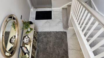 A staircase with a white railing, a grey door, and a black doormat.