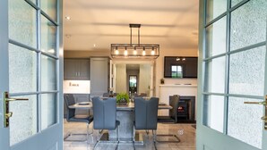 A modern kitchen with a central island, bar stools, and a fireplace. - 60 Lough Erne Golf Village · Escape Ordinary at Lough Erne! (Castle Hume/Lough Erne)