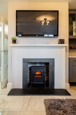 A fireplace with a TV mounted above it, a black mat in front, and a fluffy rug on the floor. - 60 Lough Erne Golf Village · Escape Ordinary at Lough Erne! (Castle Hume/Lough Erne)