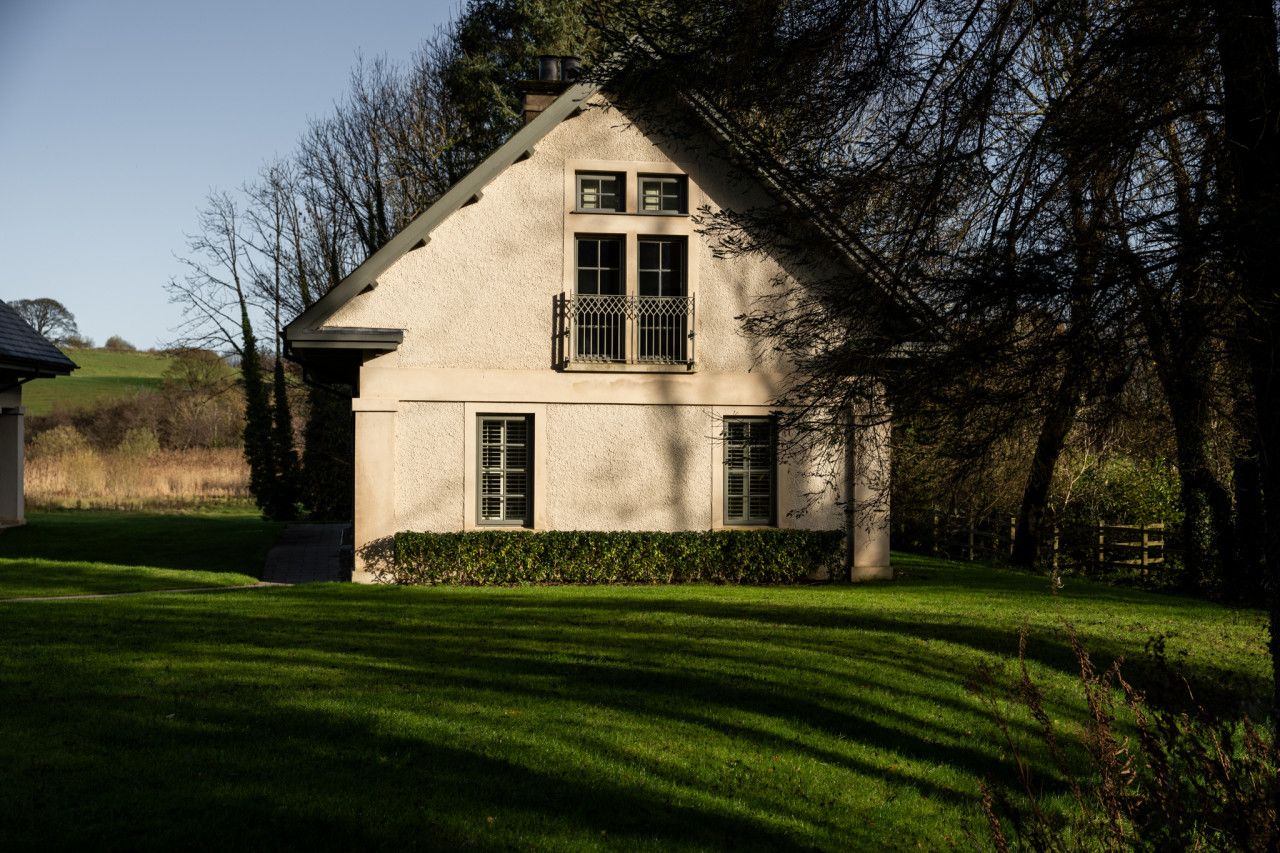 A house with a gabled roof, a balcony, and a well-maintained lawn.