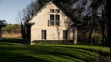 A house with a gabled roof, a balcony, and a well-maintained lawn.