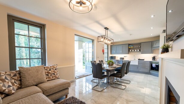 A modern kitchen with a dining area, large windows, and a fireplace. - 60 Lough Erne Golf Village · Escape Ordinary at Lough Erne! (Castle Hume/Lough Erne)