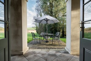 Une terrasse extérieure avec une table et des chaises, un parasol et une vue sur le paysage environnant.