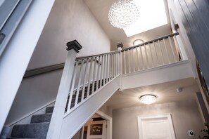 A staircase with white balusters and a chandelier. - 60 Lough Erne Golf Village · Escape Ordinary at Lough Erne! (Castle Hume/Lough Erne)