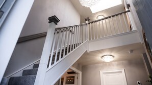 A staircase with white railings and a chandelier. - 60 Lough Erne Golf Village · Escape Ordinary at Lough Erne! (Castle Hume/Lough Erne)