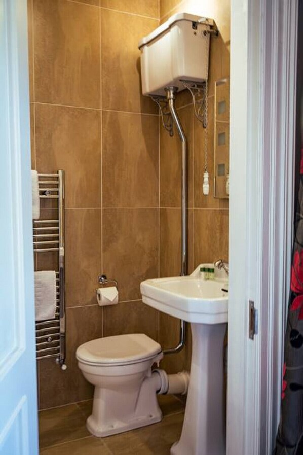 Une salle de bain équipée de toilettes, d’un lavabo et d’un porte-serviettes.