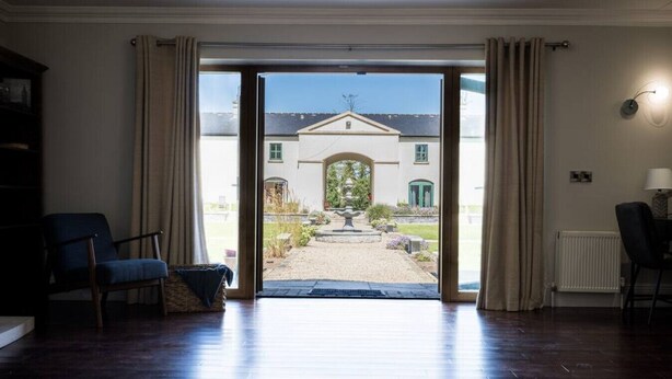 A room with a large sliding glass door leading to a garden with a fountain, a chair, and a radiator. - LE 23 · Escape Ordinary at Castle Hume No.23 ~ Luxury (Fermanagh and Omagh)