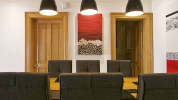 A dining area with a wooden table and six chairs, three pendant lights above, and a red abstract painting on the wall.