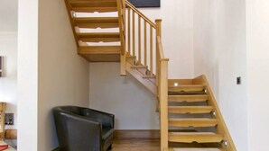 Un escalier avec des marches en bois et une rampe, menant à l’étage supérieur.