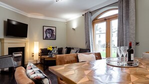 A living room with a wooden dining table, leather sofas, a flat-screen TV, and a fireplace.