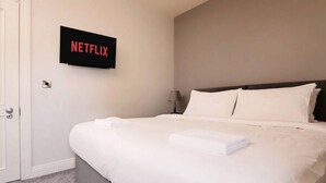 Une chambre d’hôtel avec un lit, un téléviseur fixé au mur et une porte.