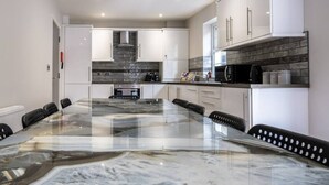 A modern kitchen with a marble island, white cabinets, and a black countertop.