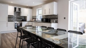 A modern kitchen with white cabinets, a large island, and a dining area with black chairs.