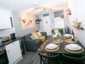 A compact living space with a kitchenette, dining area, and a sofa with cushions.