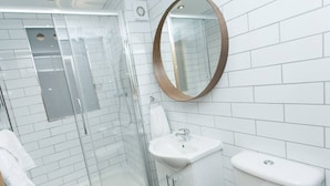 A modern bathroom with a glass-enclosed shower, a white sink, and a toilet.