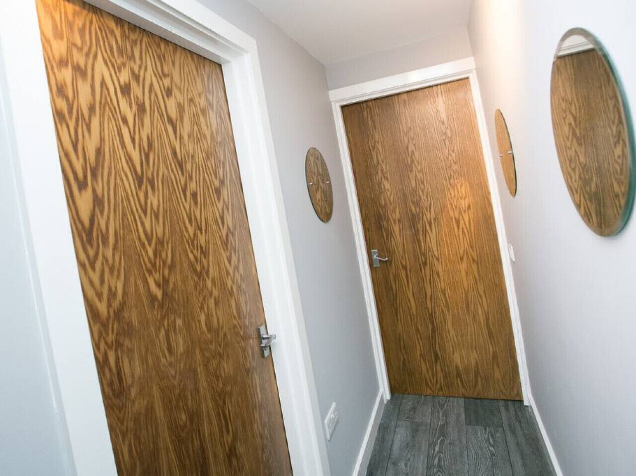 A hallway with wooden doors and a mirror on the wall.