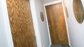 A hallway with wooden doors and a mirror on the wall.