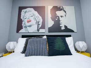 A bed with patterned pillows, a dark green leaf pillow, and a headboard with a geometric design.