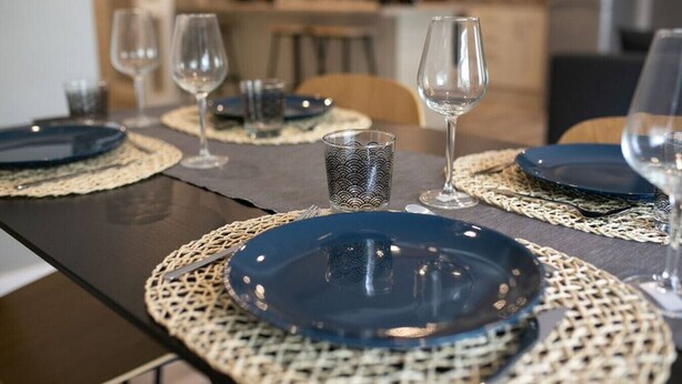 A dining table set with blue plates, clear wine glasses, and a patterned candle holder. - University Road 1 · Spacious & Modern + Central Location|Couples Break (Belfast)