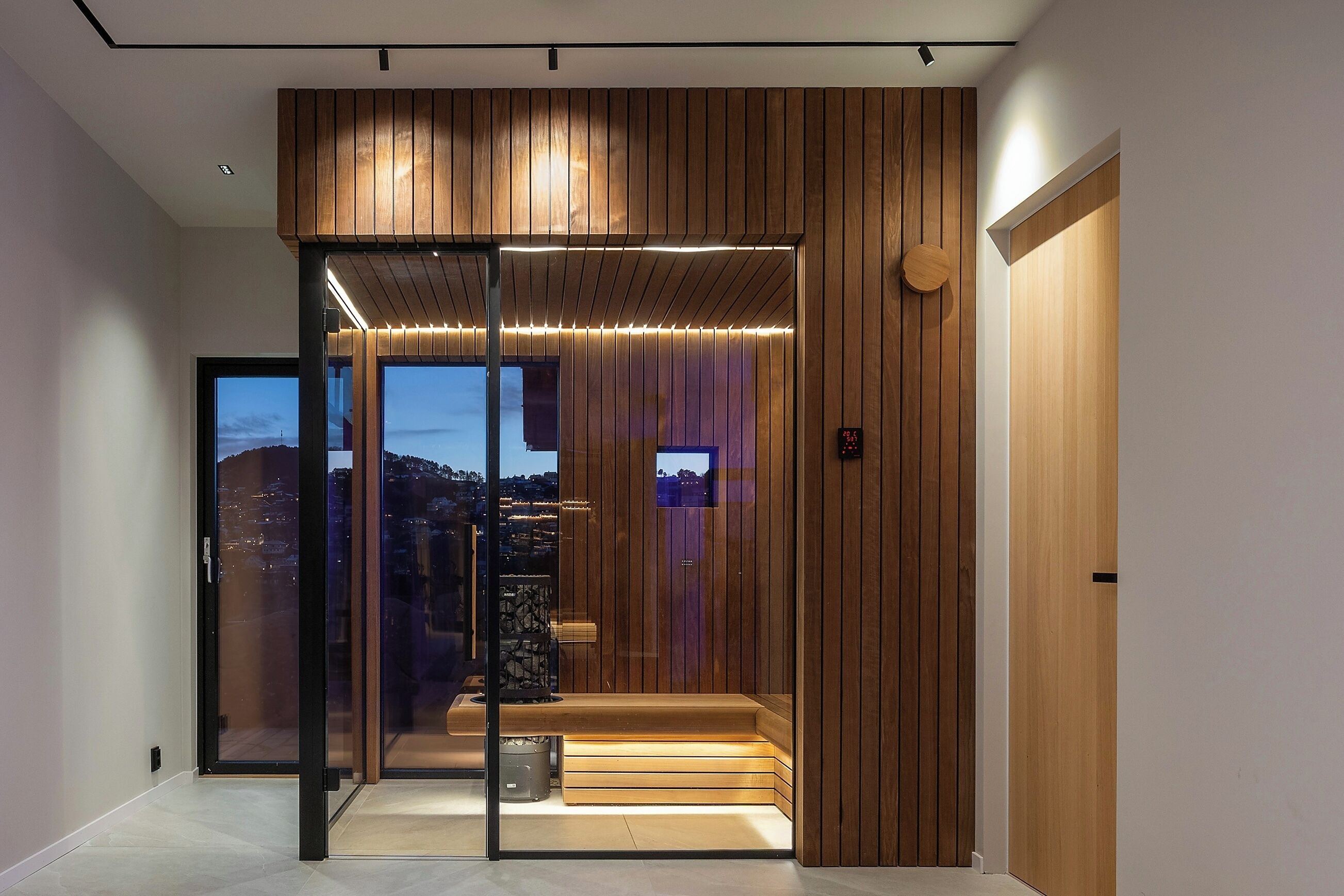 A modern interior with a sliding glass door leading to a balcony, wooden paneling on the walls, and a digital display.