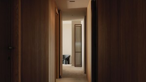 Un pasillo con puertas de madera que dan a una habitación con bañera y sillón.
