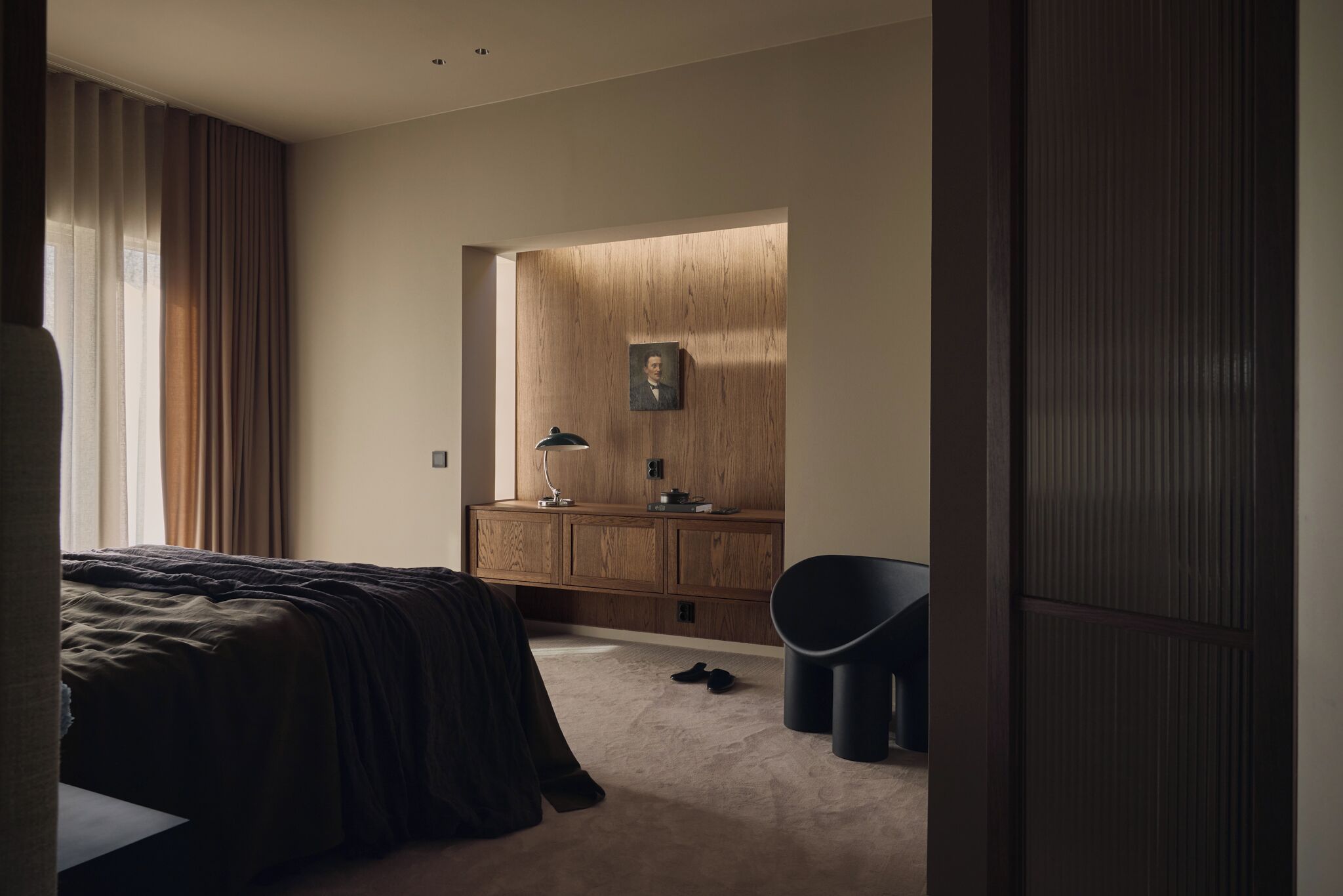 Une chambre à coucher avec un lit, une armoire en bois, un bureau avec une lampe et une chaise.