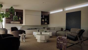 A modern living room with a sofa, armchairs, a coffee table, and a bookshelf.