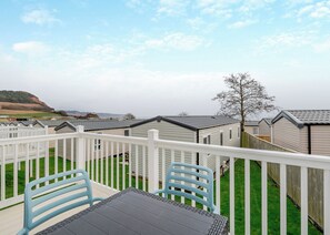 A view of a caravan park with a fenced patio area, a table, and chairs. - Otterton Premier Plus 2 (Budleigh Salterton)