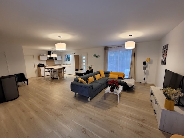 A modern living room with a sofa, coffee table, and a dining area with chairs and a table.