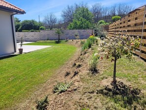 Stroll through the beautifully landscaped backyard, surrounded by lush plants and a small tree with vibrant flowers.