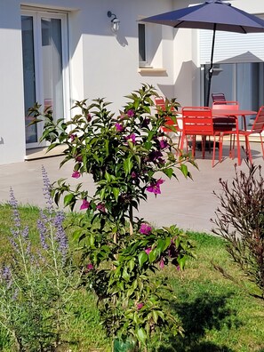 Enjoy dining and socializing in this beautifully maintained garden patio with a variety of plants and a shaded seating area.
