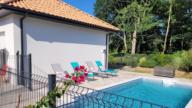 A swimming pool with lounge chairs, a white building with a tiled roof, and a fenced area with greenery. - Maison Neuve Bord de Dordogne (Lanzac)