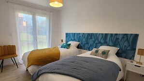 A bedroom with a large bed, a bedside table, a chair, and a window with curtains. - Maison Neuve Bord de Dordogne (Lanzac)