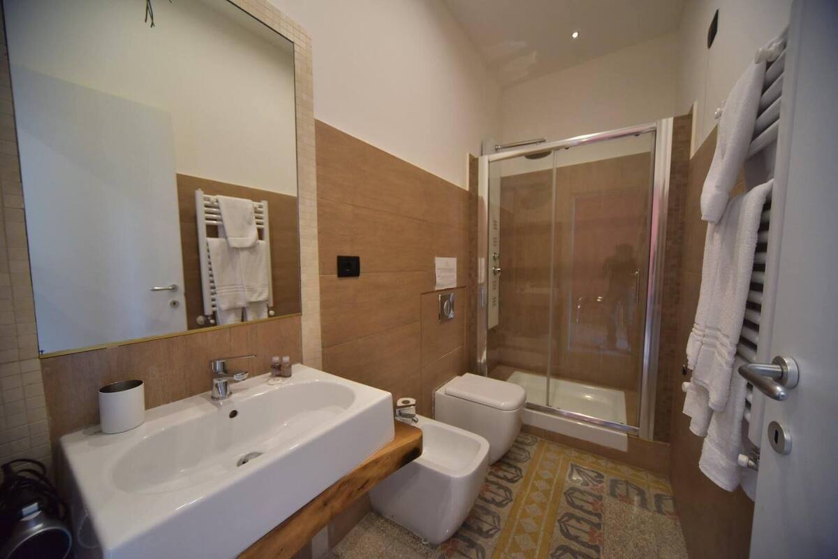A modern bathroom with a large sink, a toilet, and a glass-enclosed shower.