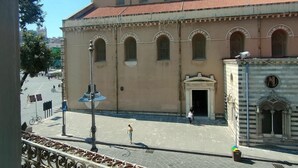 A building with a large arched entrance, a clock tower, and a tiled roof. - Duomo156 (Messina)