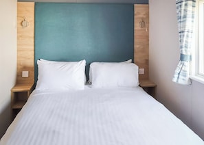 A neatly made bed with white linens, a teal headboard, and bedside lamps. - Otterton Premier Plus 3 (Budleigh Salterton)