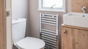 Ein kleines Badezimmer mit Toilette, Handtuchhalter, Fenster und Waschbecken.