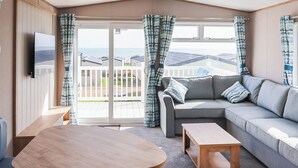 Ein gemütlicher Wohnbereich mit einer Couch, einem Tisch und einem an der Wand befestigten Fernseher.