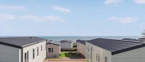 A row of mobile homes with a patio area and a view of the sea.