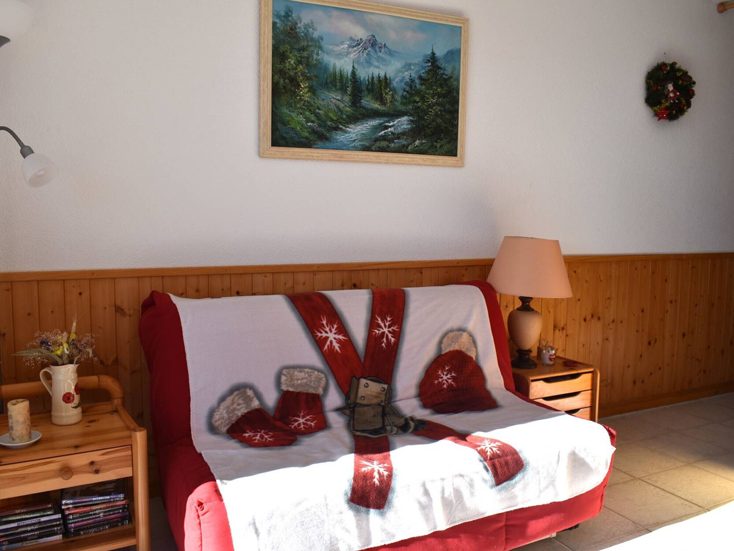 Une chambre confortable avec un lit en bois, une table de chevet avec une lampe, une bibliothèque et un tableau accroché au mur.