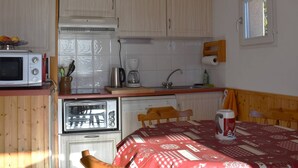 A compact kitchen with a microwave, coffee maker, and a table with a red tablecloth. - Beautiful sunny 2-room apartment (Font-Romeu-Odeillo-Via)