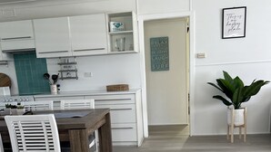 Une cuisine moderne avec des meubles blancs, une table à manger avec des chaises blanches et un plancher en bois.