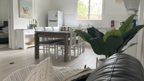 Un salon avec un canapé en cuir noir, un plaid blanc et une plante verte.