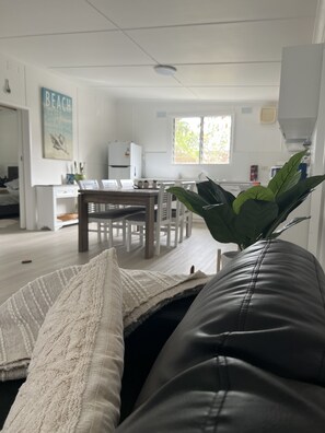 Een woonkamer met een zwarte leren bank, een witte deken en een groene plant.