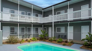 A multi-story building with balconies, a swimming pool, and outdoor seating. - Pacific Motel 01 - Free WiFi (Forster)