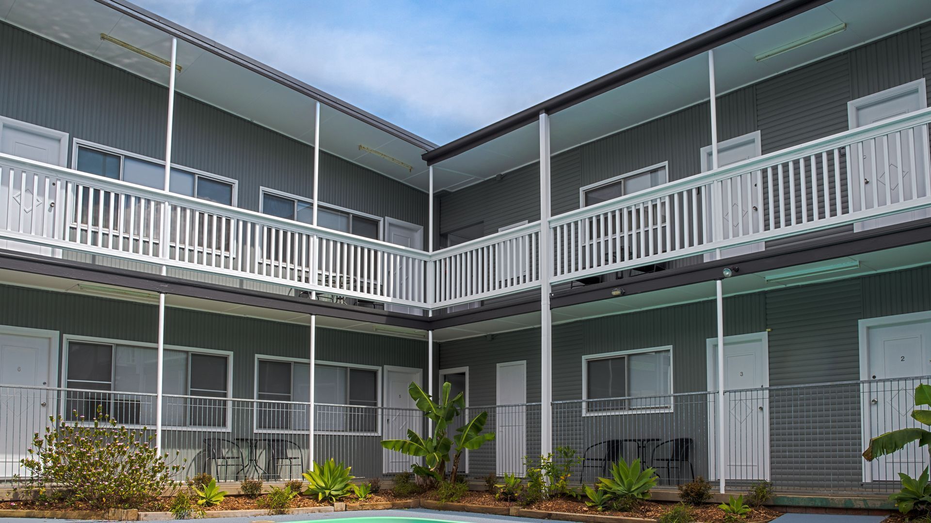 Un edificio de varios pisos con balcones, piscina y jardín.