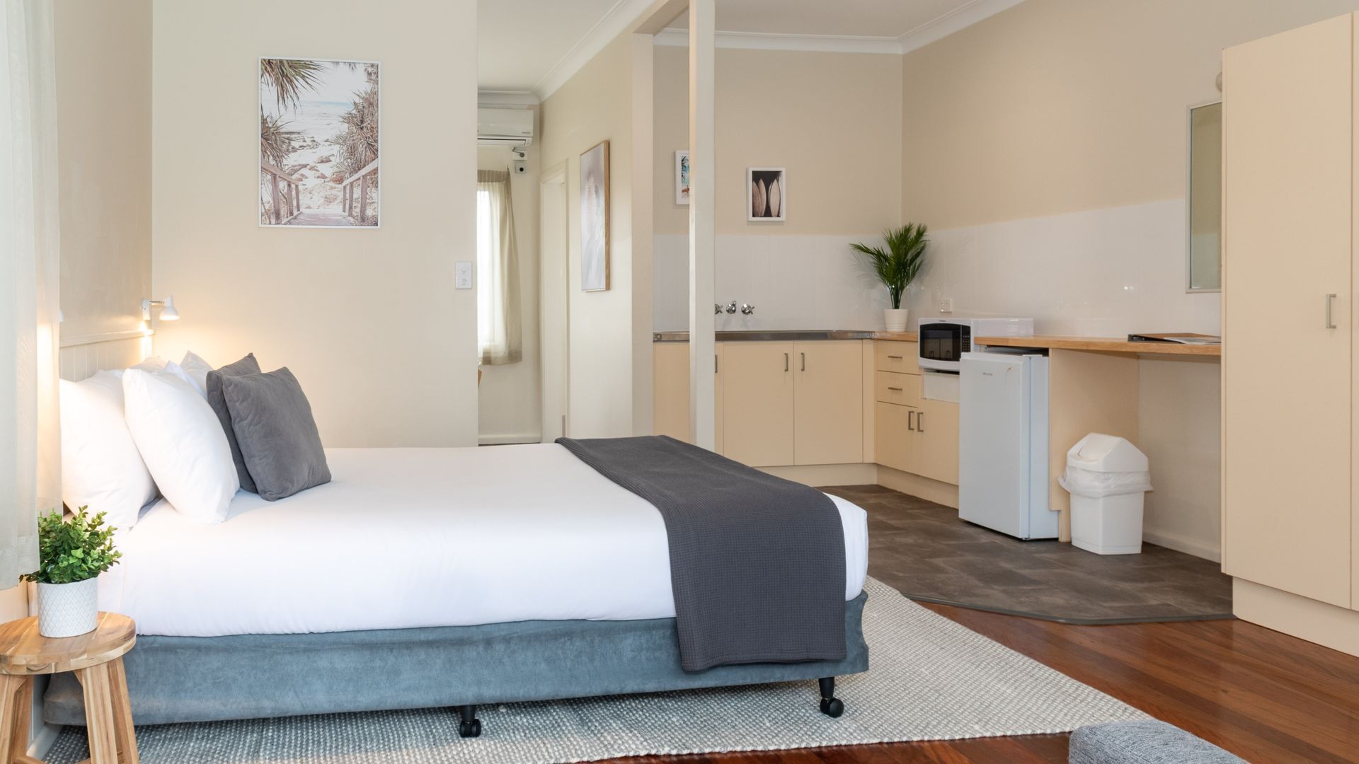 A bedroom with a bed, bedside table, and a potted plant.