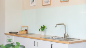 A modern kitchen with a wooden countertop, stainless steel sink, and white cabinets. - Jasmine Lodge in the heart of Forster (Forster)