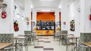 A restaurant with multiple tables and chairs, a counter with food items, and wall decorations.